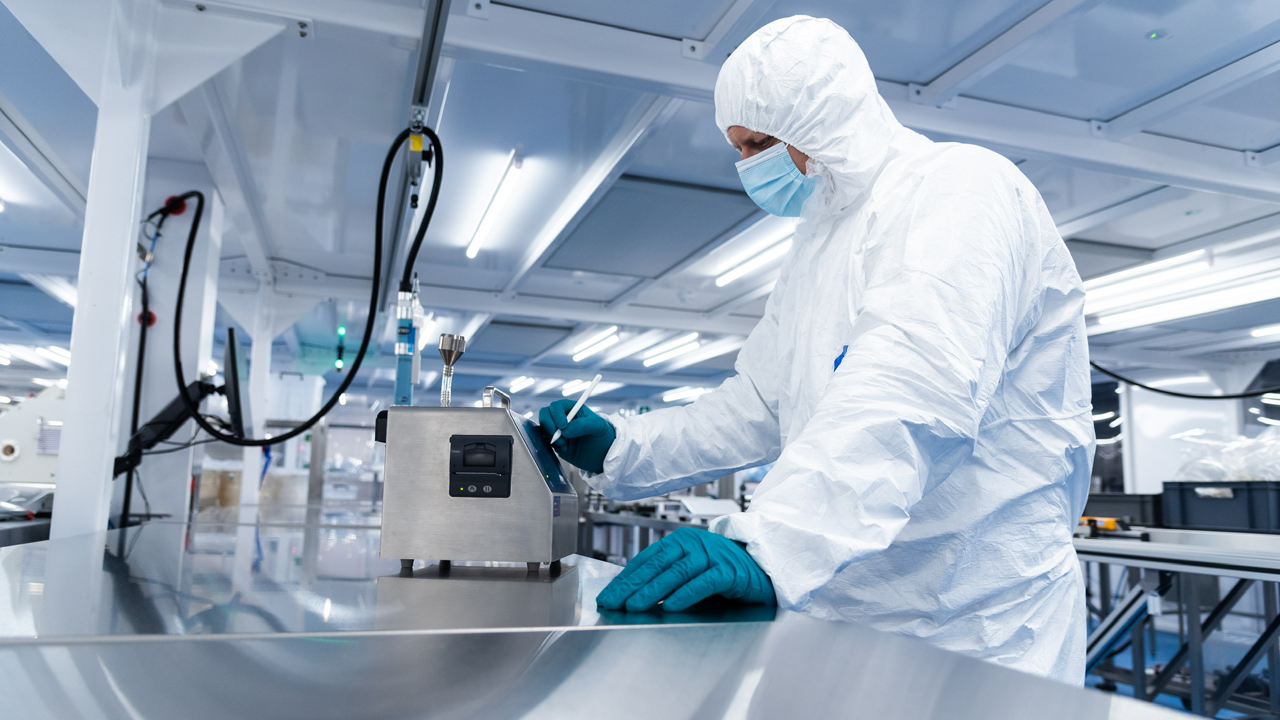 Cleanroom operator using a remote particle counter on a stainless steel bench