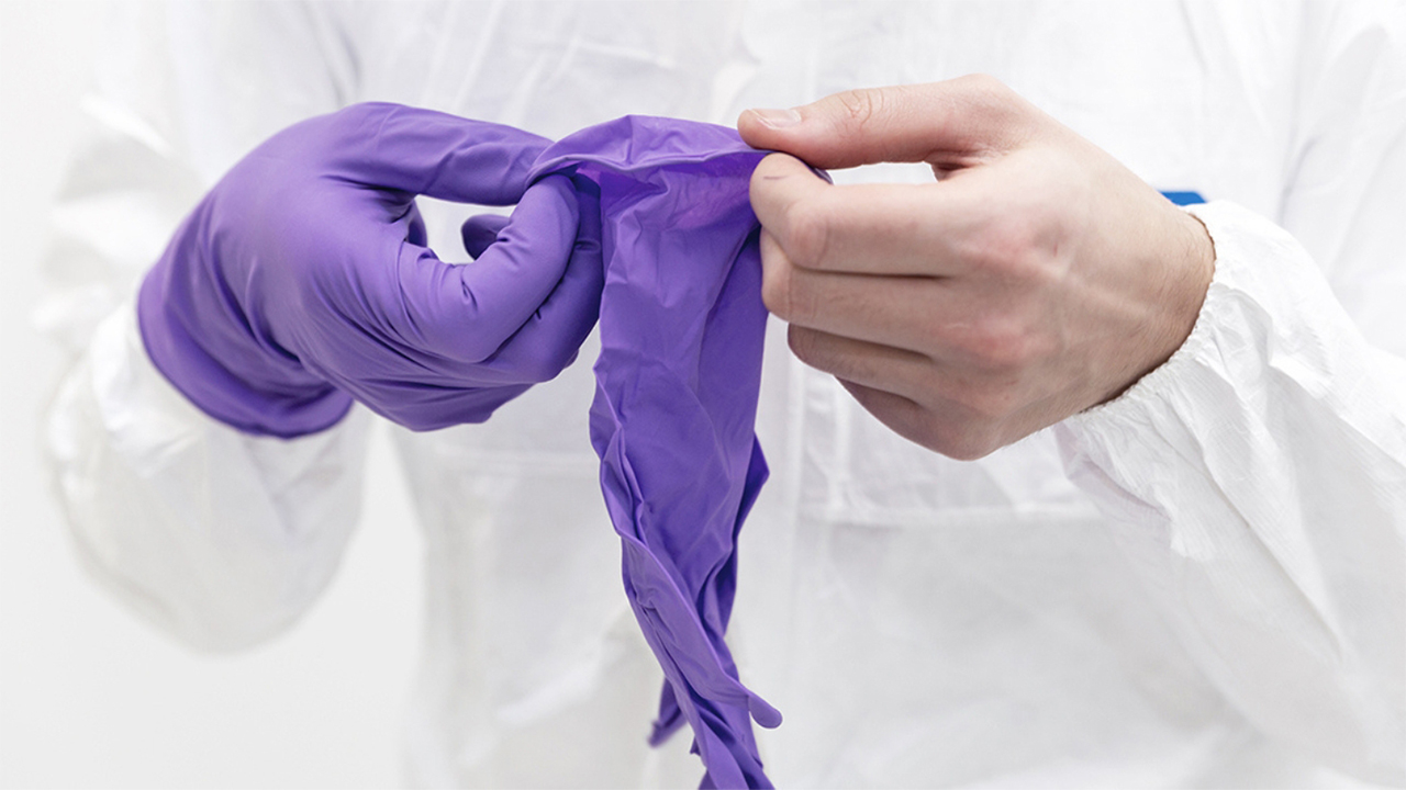 Cleanroom operator donning purple nitrile gloves